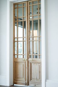 an open wooden door with glass panels on the front and back doors, in a white room