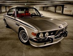 an old bmw is parked in a parking garage