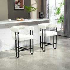 two white stools sitting in front of a counter