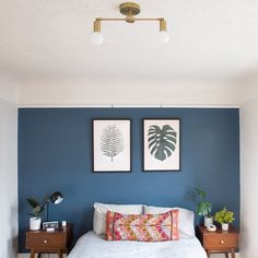 a bedroom with blue walls and white bedding, two framed pictures on the wall