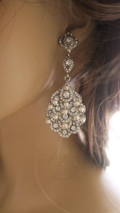 the back of a woman's head wearing earrings with pearls and crystals on them