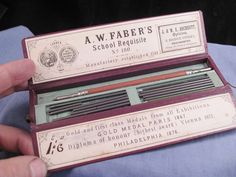 a person holding an old fashioned sewing needle set in its cardboard box with instructions on how to use it