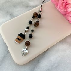 a close up of a cell phone chain on a table next to a pink flower