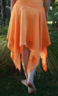 a woman in an orange dress walking through the grass