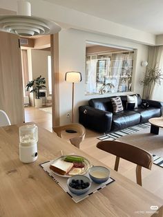 a living room filled with furniture and a wooden table topped with plates of food next to a window