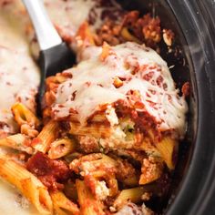 a crock pot filled with pasta and meat covered in sauce, cheese and parmesan