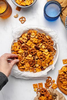 a person reaching into a bowl filled with cheetos and pretzel snacks