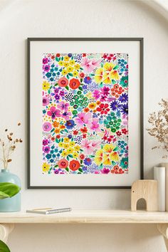 a colorful floral print hangs on the wall above a shelf