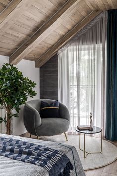 a bedroom with a round bed, chair and potted plant in the corner on the floor