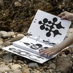 a person holding up a piece of paper with black and white designs on it