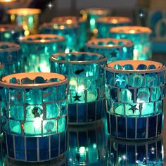 several lit candles are sitting on a table with blue and green lights in the background