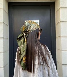 a woman standing in front of a door with a scarf on her head