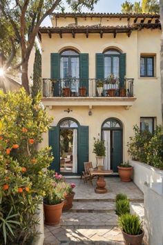 a house with green shutters and potted plants