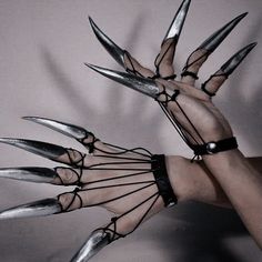 a hand with multiple claws holding something in it's palm and wearing bracelets