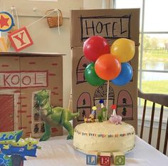 a birthday cake with balloons sitting on top of a table next to boxes and toys