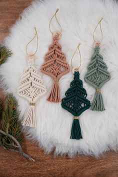 three crocheted ornaments are hanging on a white furnishing with pine needles