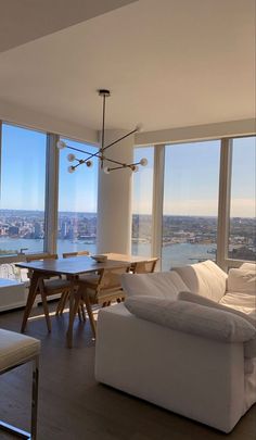 a living room filled with furniture and large windows overlooking a cityscape in the distance