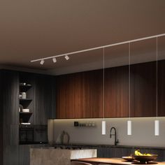 a modern kitchen with wooden cabinets and counter tops, lights hanging from the ceiling over the island