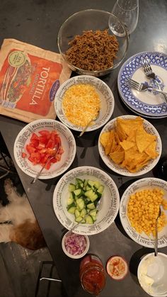 the table is full of different types of food including chips, cucumbers and tomatoes