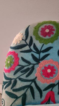 a blue pillow with flowers on it sitting on a table next to a white wall