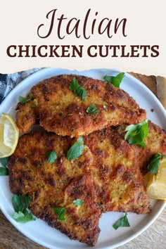 chicken cutlets on a white plate with lemon wedges