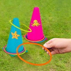 a hand is holding a plastic cone with an octopus on it and another toy in the background