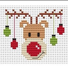 a cross stitch christmas ornament with ornaments hanging from it's sides and a reindeer face on the front