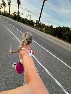 a woman is running down the street with her arm in the air