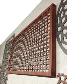 two metal and wood wall art pieces on the side of a building, one with holes in it