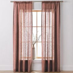 a window with sheer curtains and a vase in front of it on top of a hard wood floor