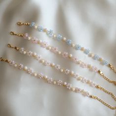 four necklaces with pearls and gold chains on a white sheet, close up view