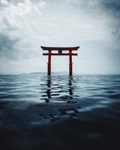 a red tori floating in the ocean under a cloudy sky