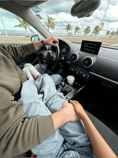 a man sitting in the driver's seat of a car with his hands on the steering wheel