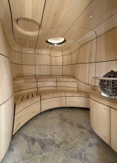 the inside of a wooden room with benches and round lights on it's ceiling