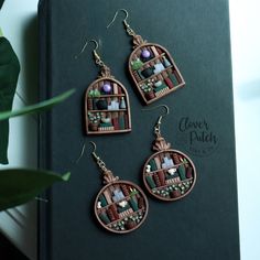 three pieces of jewelry sitting on top of a green book next to a potted plant