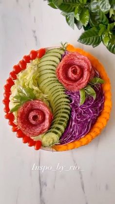 a plate filled with sliced vegetables on top of a white table next to a potted plant