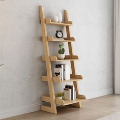 a wooden shelf with books on it in front of a white wall and a plant