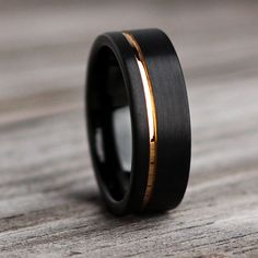 a black and gold wedding ring on top of a wooden table