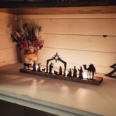 a nativity scene is displayed on a mantle with candles and christmas tree in the background