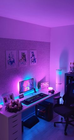 a desk with a computer and some pictures on it in a room that has purple lighting