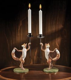 two figurines holding candles on top of a wooden table next to each other