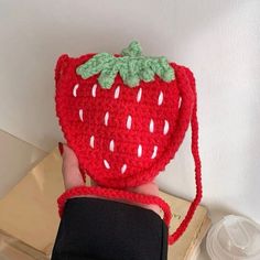 a crocheted strawberries purse being held by someone