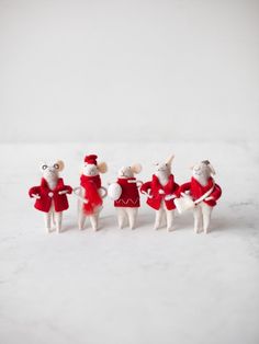 four mice dressed in red and white are lined up on a snow - covered surface