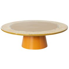 an orange and white cake plate sitting on top of a wooden stand with yellow trim