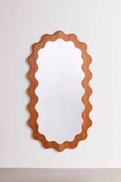 an oval wooden mirror hanging on the wall