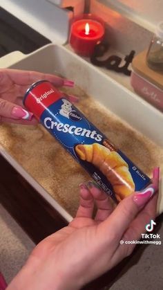 a woman holding a tube of toothpaste in front of a baking pan filled with cookies