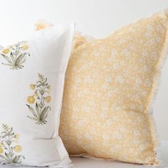 two yellow and white pillows sitting next to each other