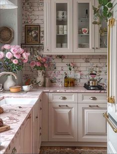 a kitchen with white cabinets and pink flowers