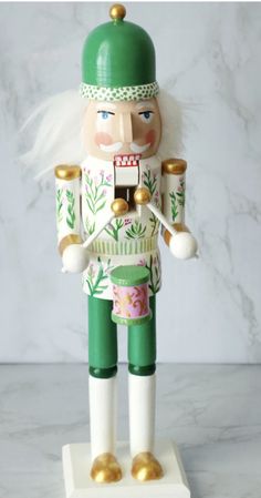 a nutcracker is standing on a marble surface with gold trimmings and green hat