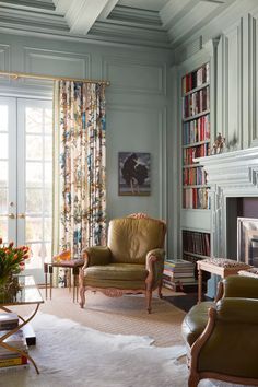 a living room filled with furniture and bookshelves next to a fire place in front of a window